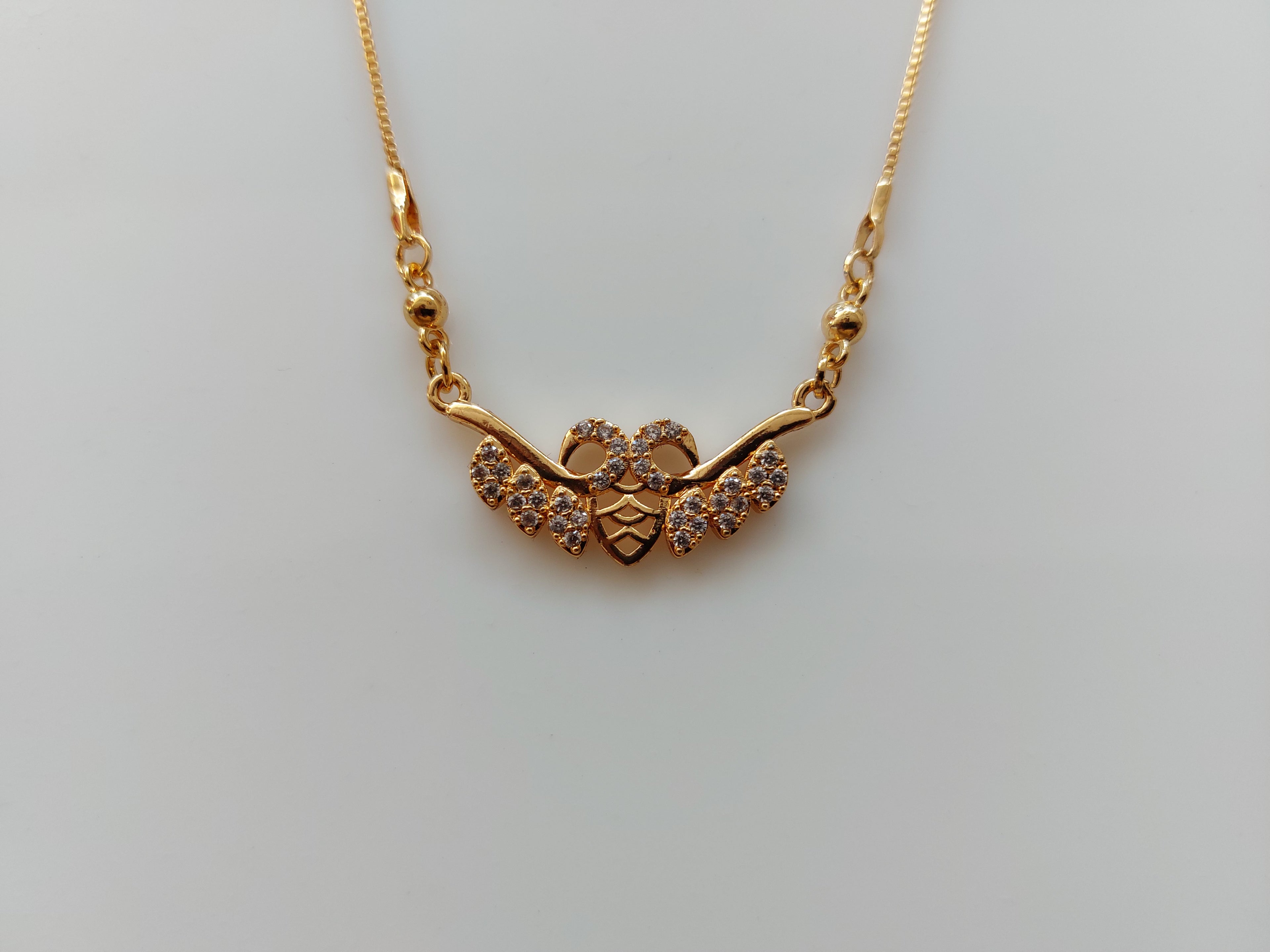 A gold chain necklace with a decorative pendant featuring a central heart and three curved branches adorned with small clear stones, shown on a plain light gray background.